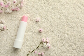 Lip balm and gypsophila flowers on white textured background, flat lay. Space for text