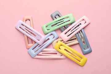 Different hair clips on pink background, flat lay