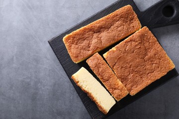Tasty Japanese Castella sponge cake on grey table, top view. Space for text