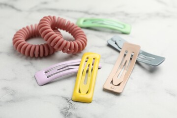 Different hair accessories on white marble table, closeup