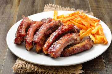 Roasted pork ribs and potato fries on white plate
