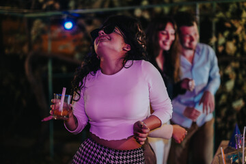 A group of friends joyfully dancing and celebrating at an evening party. They are enjoying drinks and music in a lively social gathering in a cheerful and energetic setting.