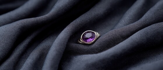 Fototapeta premium Close-up of a ring resting on a dark grey fabric. the ring has a large, oval-shaped amethyst stone in the center, which is a deep purple color.