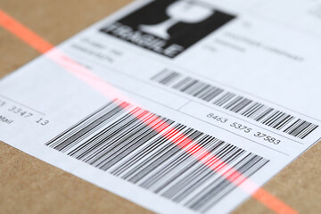 Parcel with label, closeup. Red laser light on barcode for scanning