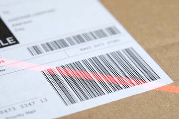 Parcel with label, closeup. Red laser light on barcode for scanning