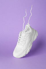 Stylish white sneaker in air against violet background