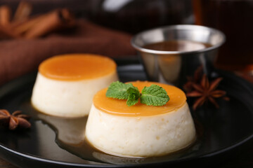 Tasty puddings with caramel sauce served on table, closeup