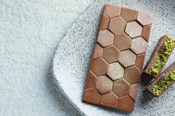 Delicious Dubai chocolate with pistachios and knafeh on light textured table, top view. Space for text