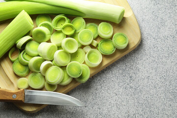 Chopped leeks and knife on grey table, top view. Space for text