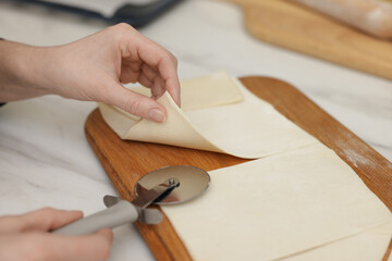 Woman cutting dough at light table, closeup. Making croissants