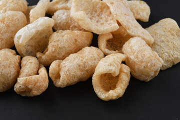 チチャロン　メキシコやフィリピンで食べられる豚の皮（豚皮）のスナック　コピースペースあり　黒背景 Chicharon　(chicharrón, chicharron), pork skin (pig skin) snack, eaten in Mexico and the Philippines, copy space available, black background