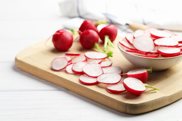 Fresh whole and cut radishes on white wooden table, closeup