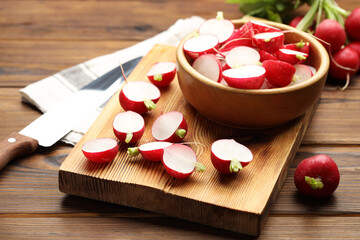 Fresh cut and whole radishes on wooden table, closeup