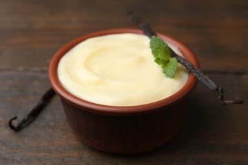 Tasty vanilla pudding, mint and pods on wooden table, closeup