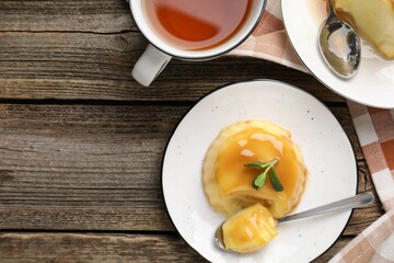 Delicious pudding with caramel sauce and mint served on wooden table, flat lay. Space for text