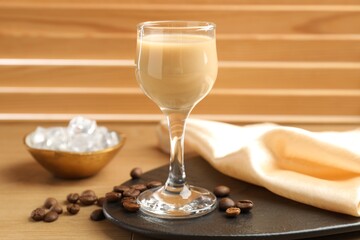 Coffee cream liqueur in glass, ice and beans on wooden table
