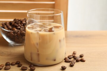 Coffee cream liqueur in glass and beans on wooden table, closeup. Space for text