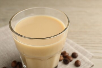 Coffee cream liqueur in glass and beans on table, closeup