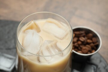 Coffee cream liqueur in glass, ice cubes and beans on table, closeup