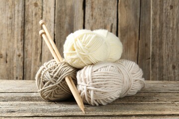 Skeins of yarn and knitting needles on wooden table, closeup