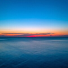 Naklejka premium Serene ocean sunset with blurred horizon.