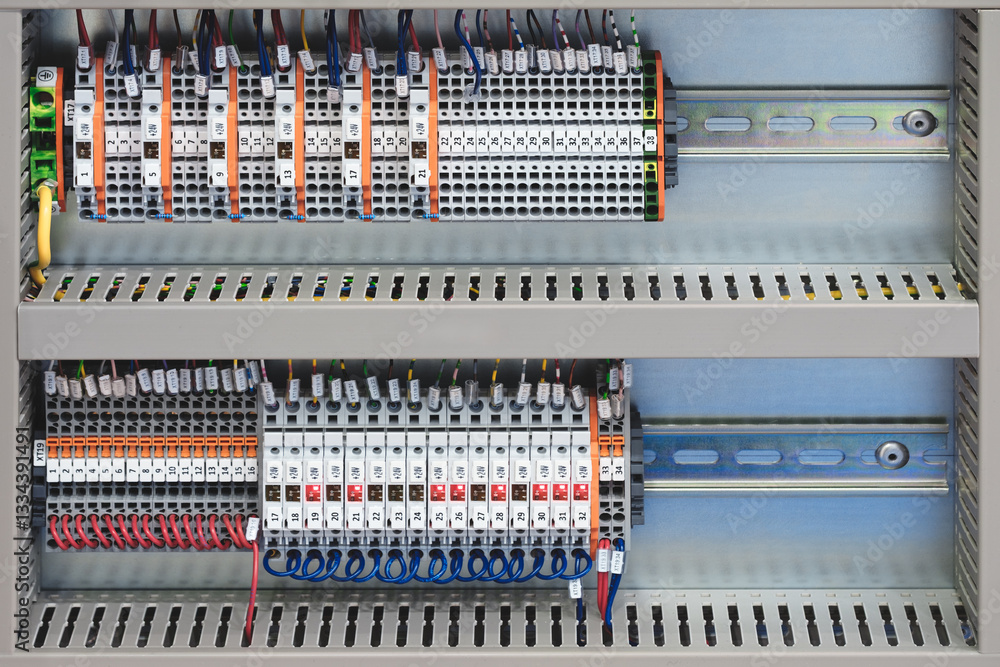 Poster a row of electrical boxes with a lot of wires and cables. the boxes are labeled with numbers and let