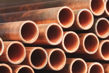 A row of pipes with a brownish color. The pipes are stacked on top of each other. industrial concept background