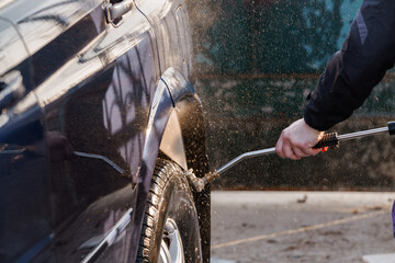 Close-Up of a Person Pressure Washing a Car Tire and Fender Outdoors