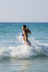 Fototapeta premium A happy woman enjoys swimming in the ocean among large waves. Concept of travel, leisure, and relaxation.