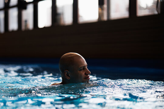 African american man swimming in pool with blue water 