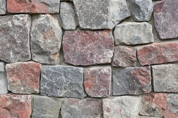 Obraz premium Rustic stone wall texture. Close-up view of irregular, fitted stonework. Different shades of gray and red