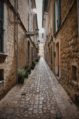 A narrow alleyway with a stone wall and a sign on the wall majorca spain
