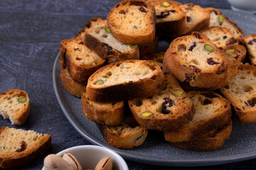 Croutons with dried cranberries and pistachios on a ceramic plate on a grey table. Close-up