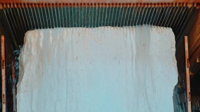 Water-assisted wire cutting process in a marble processing factory. Thin wire saws are used to cut marble blocks into equal sections.
