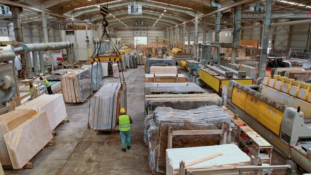 Overview of the production line in a marble processing factory. Large stone slabs are managed through an integrated system for processing, cutting, and transportation.
