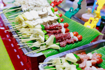 Grilled meat with tomatoes cherry and green chilies arrange by skewers on banana leaves. BBQ skewers on bananas leaves