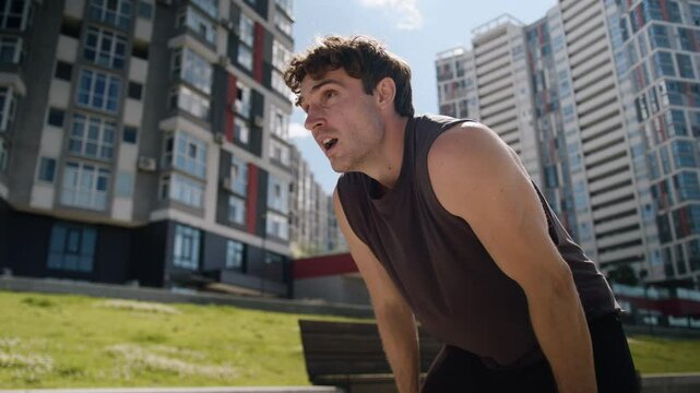 Tired Caucasian European young man sportsman running jogging morning training workout cardio exhausted guy male hard breathing stopping rest relaxing pause city outdoor sport healthy lifestyle runner