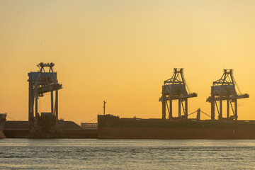 the gantry crane at the port is set against sunset sky at Europoort, Rotterdam