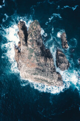 Aerial view a big rock in the sea with white split water