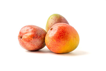 Three mangoes are sitting on a white background. They are ripe and ready to eat. The mangoes are positioned in a row, with one on the left, one in the middle, and one on the right