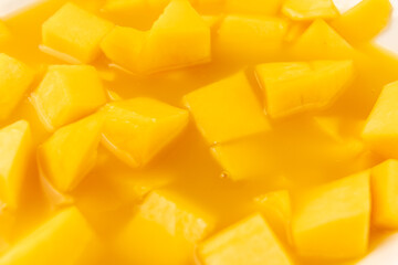 A bowl of sliced mangoes in a yellow sauce. The sauce is thick and the mangoes are cut into small cubes