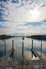 Fototapeta premium A gorgeous landscape with ocean water, homes and boats on the water, blue sky and clouds, lush green palm trees at sunrise in Clearwater Florida USA