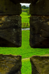 the countryside near Alnwick in Northumberland, England seen through a merlon in the wall