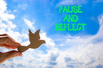 Pause and reflect symbol. Concept words Pause and reflect. Beautiful blue sky clouds background. Businessman hand, wooden birds. Business motivational lifestyle pause and reflect concept. Copy space.