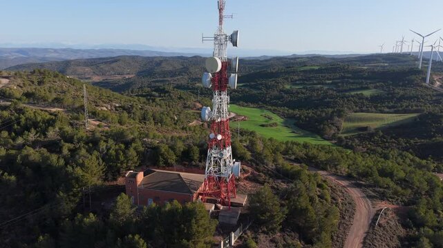 Metraje a&eacute;reo en 4K de una torre de telecomunicaciones en un paisaje monta&ntilde;oso con antenas y sistemas de transmisi&oacute;n. Los aerogeneradores en el fondo resaltan la combinaci&oacute;n de comunicaci&oacute;n y energ&iacute;a 