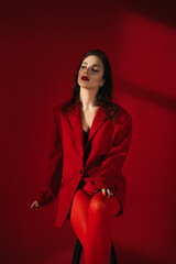 Young Woman In Red Suit With Red Lips Posing On The Red Background