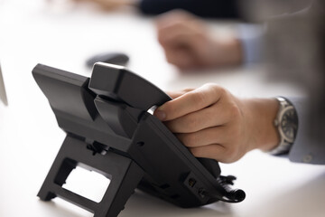 Hand of businessman touching handset of office landline phone. Office employee, manager, director...