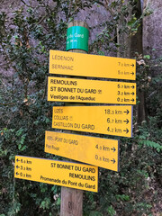 Pont du Gard, Provence, France: close-up of official yellow GR6 hiking trail sign pointing towards Uzes, Ledenon and local villages in Gorges du Gardon, UNESCO Biosphere Reserve