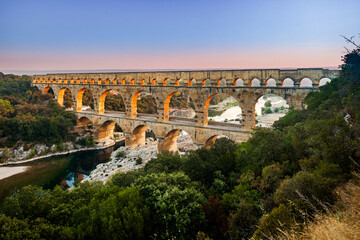 Pont du Gard, ancient Roman aqueduct bridge, elevated view, river bend and complete arches, early morning golden light, Gorges du Gardon, natural landscape, UNESCO Biosphere Reserve, Provence, France