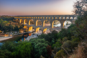 Pont du Gard, ancient Roman aqueduct bridge, elevated view, river bend and complete arches, early morning golden light, Gorges du Gardon, natural landscape, UNESCO Biosphere Reserve, Provence, France